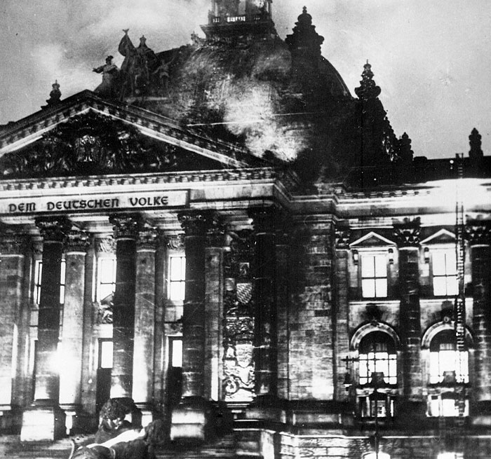 Historic black and white photo of a dramatic building facade with smoke rising, a powerful photo from all over the world.