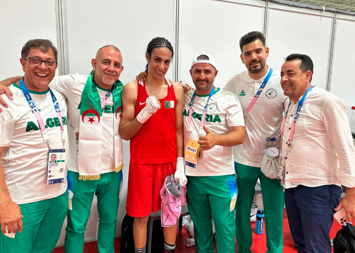 Imane Khelif with team members, wearing boxing gear and Algeria shirts, amid Y chromosome gene controversy.