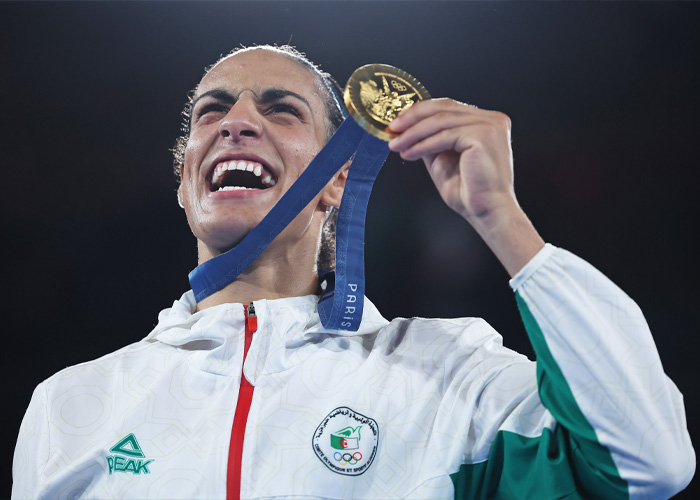 Imane Khelif holding gold medal, celebrating victory, highlighting controversy over Y chromosome gene admission.