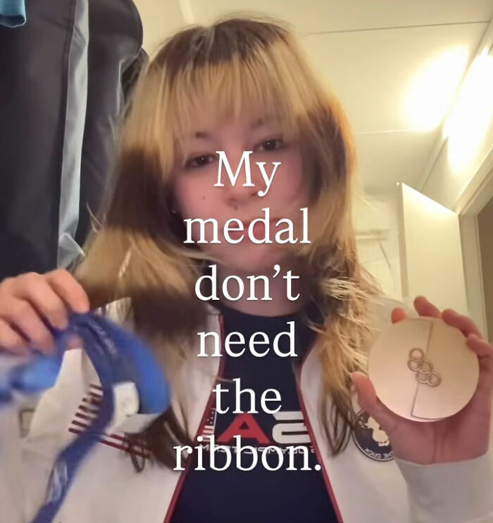US figure skater holding broken gold medal in celebration, showing resilience despite medal damage and controversy.