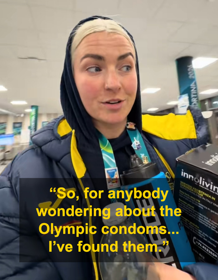 Female athlete in winter jacket holding items in Olympic Village, highlighting athletes running out of rubbers in just three days.