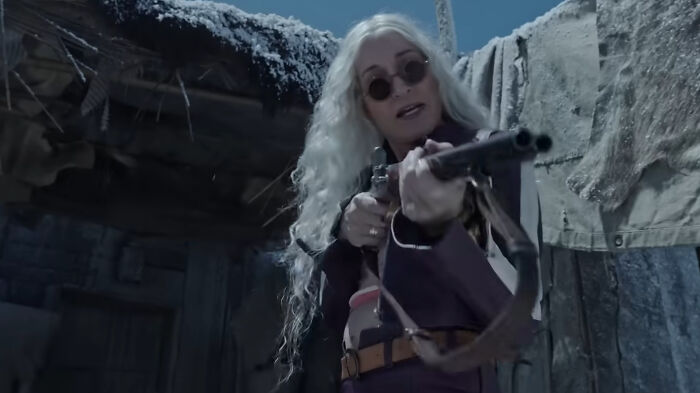 Character with white hair and sunglasses aiming a rifle in a dark snowy village scene from One Piece season 2 trailer. - 2