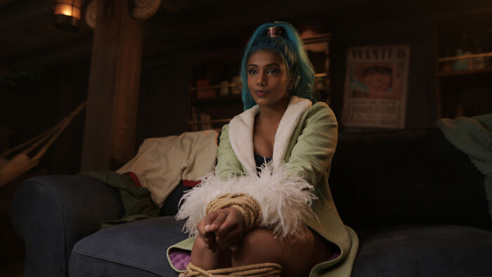 Young woman with blue hair and green robe tied with rope on a couch, related to One Piece season 2 casting choice debate. - 5