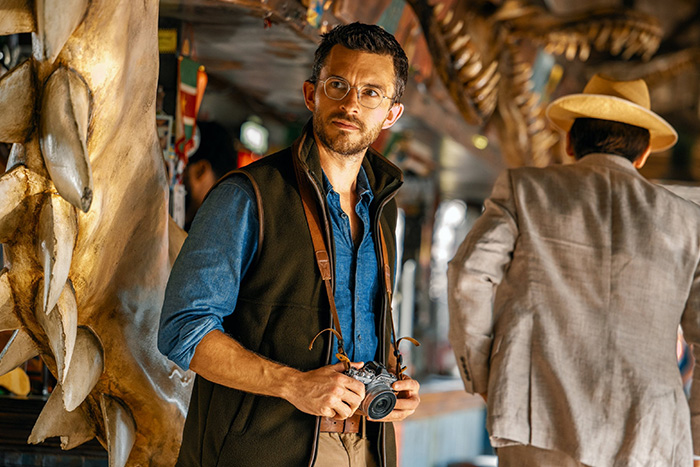 Man with glasses holding a camera in a vibrant setting, representing Oscar nominated movies 2026 atmosphere.