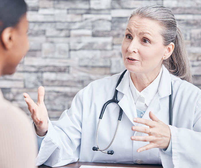 Doctor in white coat with stethoscope talking to patient, illustrating common patient actions affecting doctors and nurses.