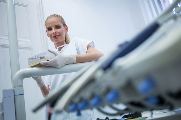Female healthcare professional in gloves holding medical tools, illustrating common patient actions that affect doctors and nurses.