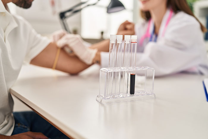 Patient having blood drawn by nurse with test tubes in foreground showing patient actions affecting doctors and nurses