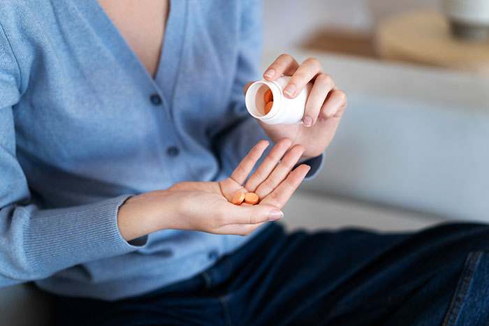 Patient holding pills from a bottle, illustrating common things patients do that affect doctors and nurses negatively.