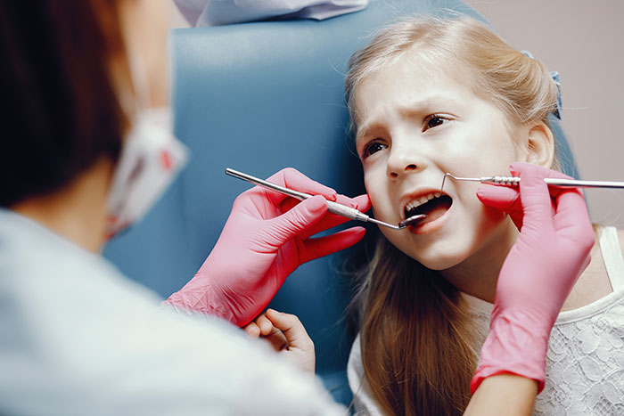 Young patient at dental checkup with dentist examining teeth, highlighting things patients do that affect doctors and nurses.