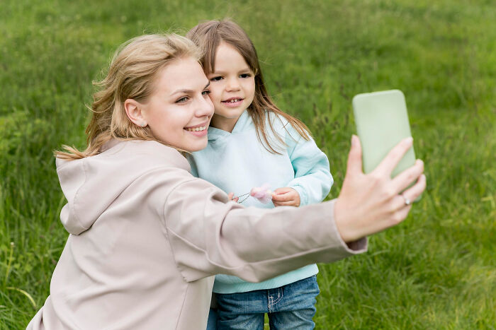 Woman and child outdoors taking a selfie, illustrating surprisingly petty things people admit they secretly judge others for.