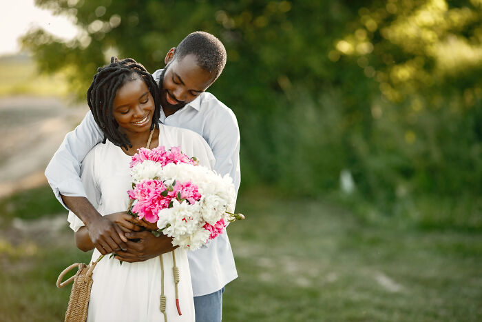 Couple embracing outdoors with bouquet of flowers, illustrating surprisingly petty things people secretly judge others for.
