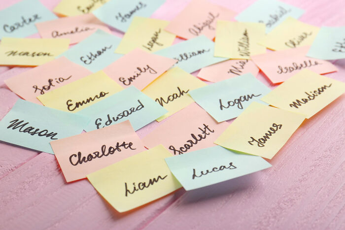 Colorful sticky notes with handwritten names scattered on a pink surface illustrating petty things people secretly judge.