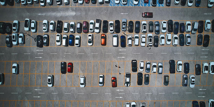 Aerial view of a large parking lot with different cars parked, illustrating petty things people secretly judge others for.