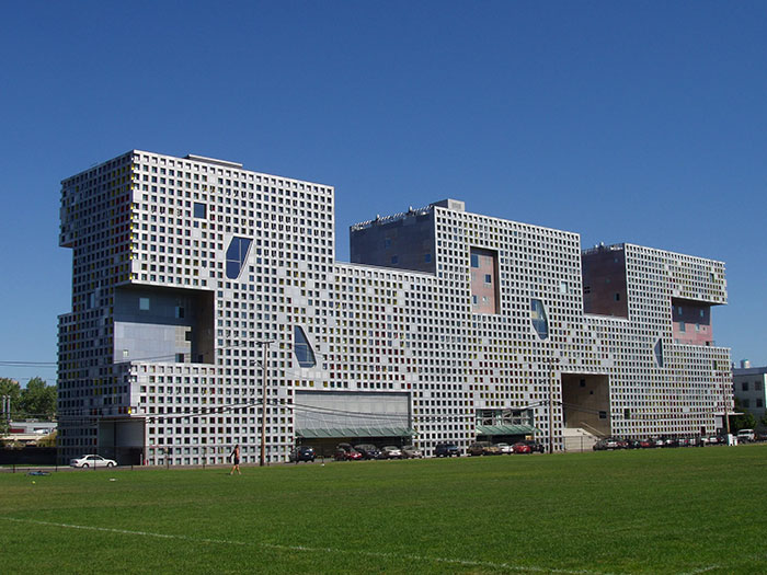 Modern architectural malpractice visible in a large, unconventional building with a grid-like facade and cutout windows.