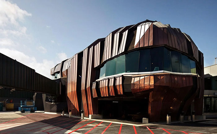 Futuristic building with copper panels and irregular design, an example of architectural malpractice in costly ugly structures.