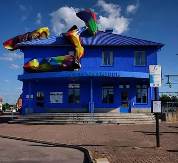 Bright blue building with colorful abstract sculptures on the roof, seen as an example of architectural malpractice costs.