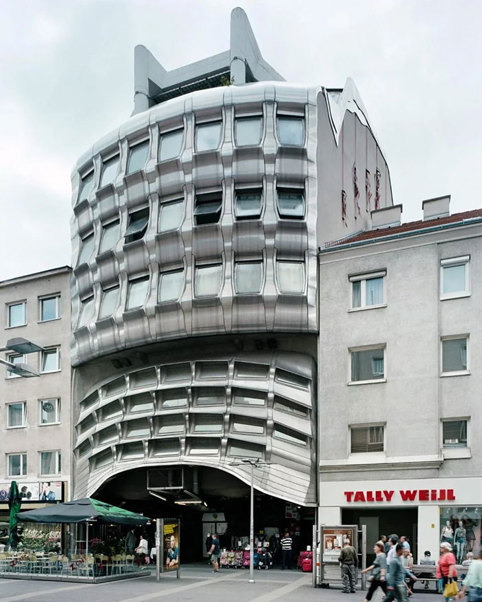 Metal-clad building with distorted windows and curved facade representing architectural malpractice in urban area.
