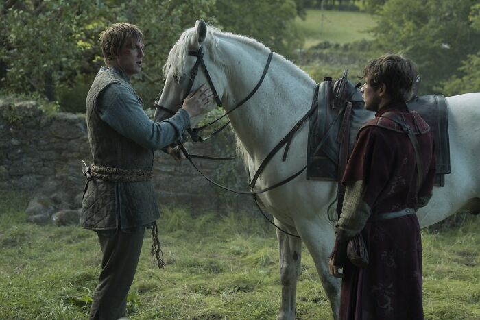 Two men in medieval clothing with a white horse, scene reflecting changes in Knight of the Seven Kingdoms finale adaptation.