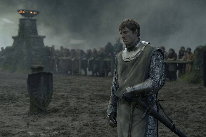 Knight in armor standing on muddy ground with a crowd behind, representing AKOTSK skipping a major book scene in episode 4.