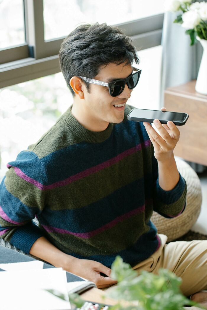 Man wearing sunglasses speaking into a smartphone, illustrating people silently judge others if they do these things.