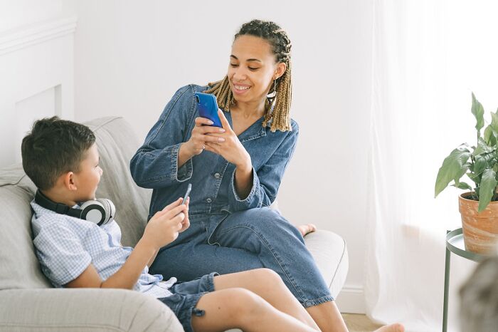 Woman and boy sitting on a couch using smartphones, illustrating people silently judge others in everyday situations.