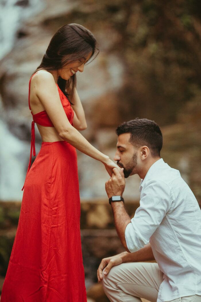Man showing respect and affection to his partner by gently kissing her hand in a romantic outdoor setting