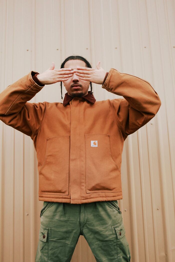 Man in brown jacket covering his eyes, symbolizing how married men react when they see a hot woman without disrespecting.