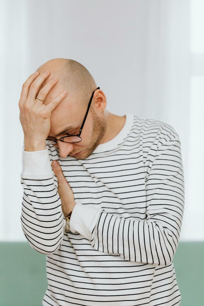 A bald man wearing glasses and striped shirt, showing a stressed reaction about disrespecting yourself or your partner.