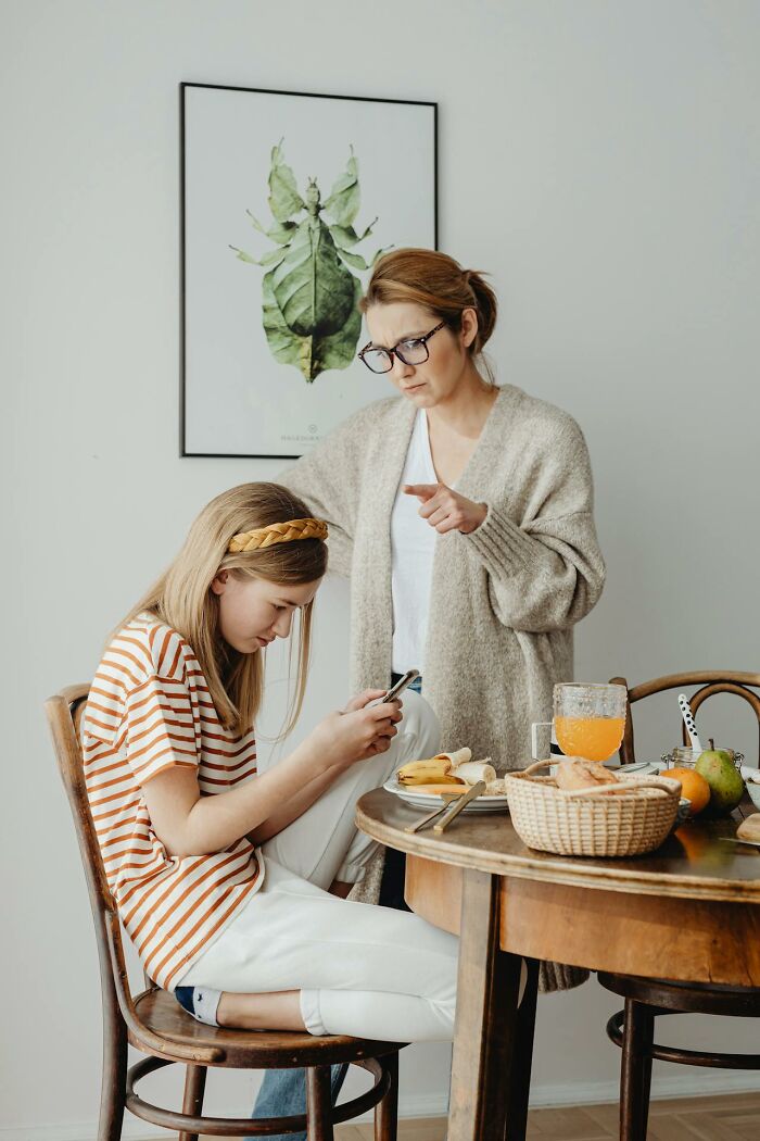 Woman scolding a teenage girl ignoring her phone, highlighting tense moments that signal immediate disaster in communication.