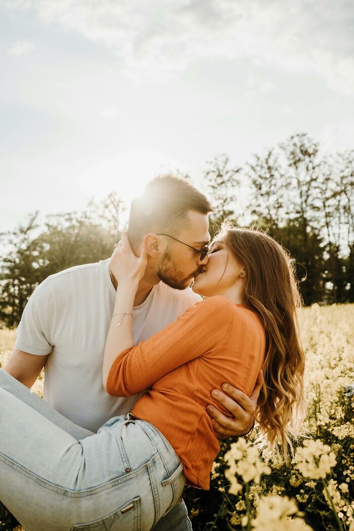Couple sharing a romantic kiss in a sunlit field, symbolizing respect and love in a married relationship.