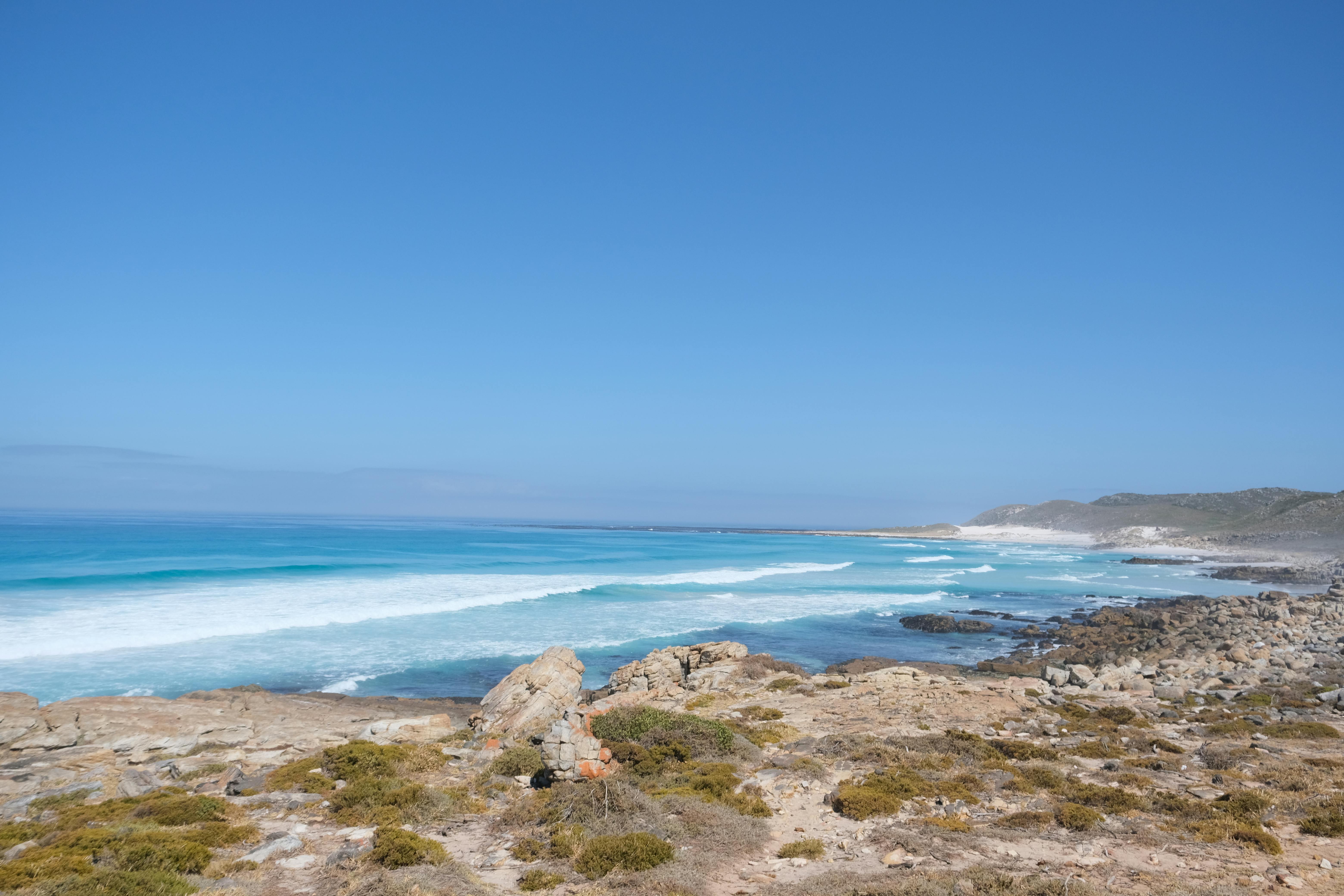 Rocky coastline with waves crashing under clear blue sky, evoking the feeling of living out of a suitcase and questioning success. Rocky coastline with waves crashing under clear blue sky, evoking the feeling of living out of a suitcase and questioning success.