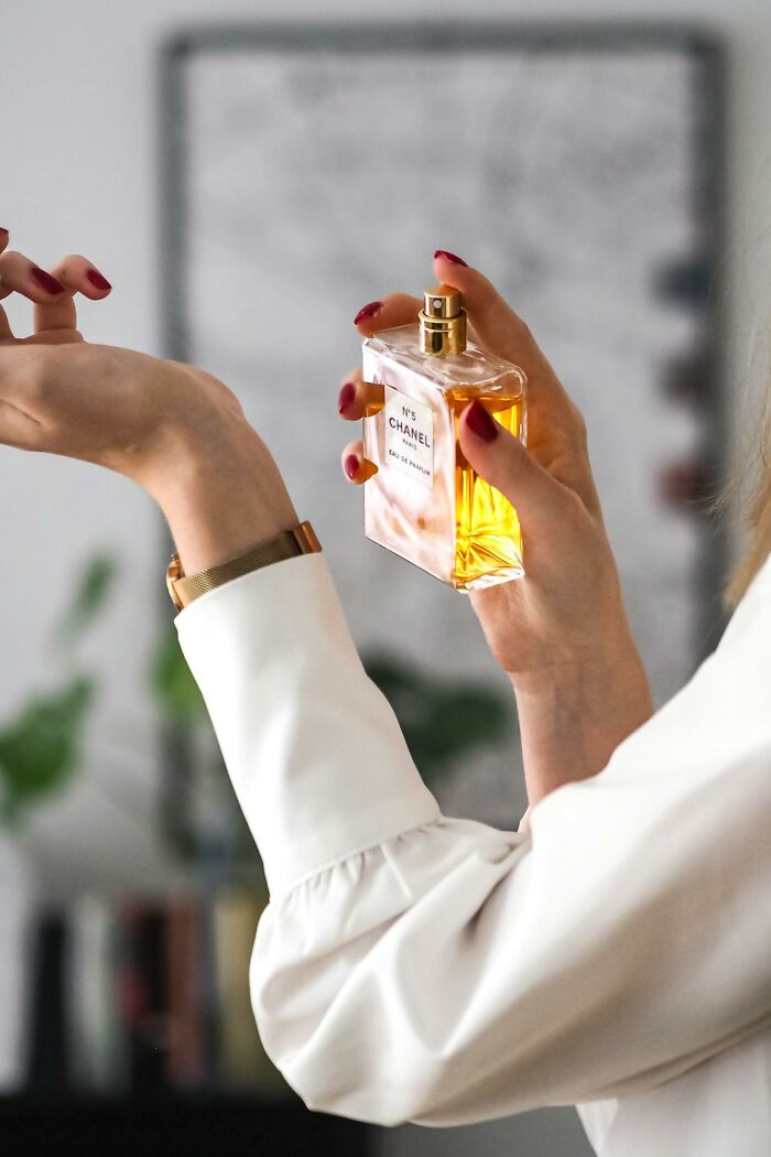 Woman spraying perfume on wrist, illustrating dramatic women who traumatized men in toxic relationships and behaviors.