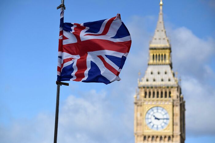 Union Jack flag waving with Big Ben clock tower in the background representing UK citizenship test and British identity.