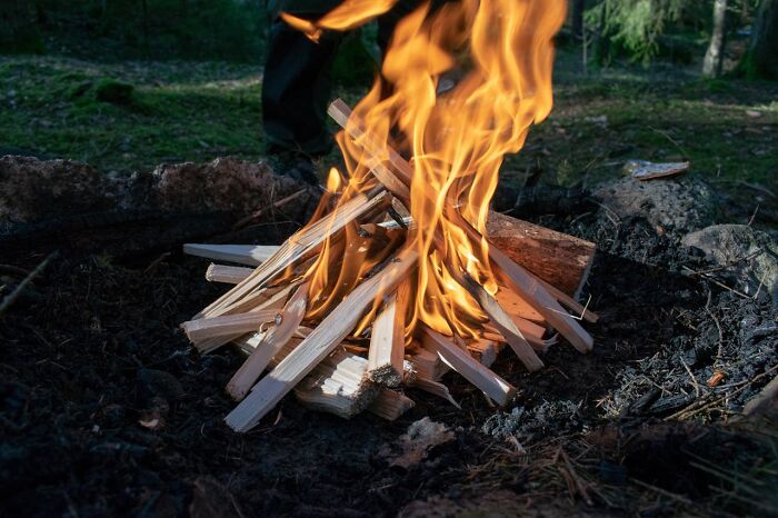 A campfire burning dry wooden sticks outdoors, symbolizing moments causing others to take a long pause.