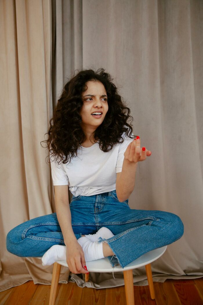 Young woman with curly hair looking confused and frustrated, expressing disbelief at stupid things said causing long pause moments.