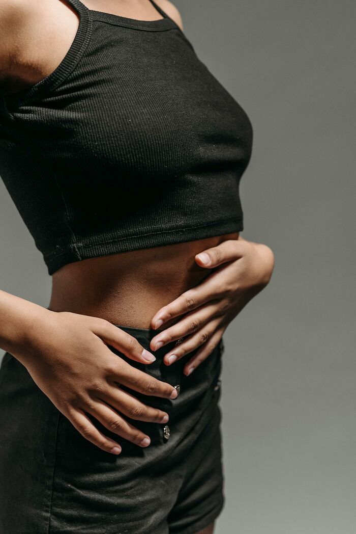 Woman in black crop top and shorts holding her waist, illustrating women traumatized men in unhinged toxic ways.