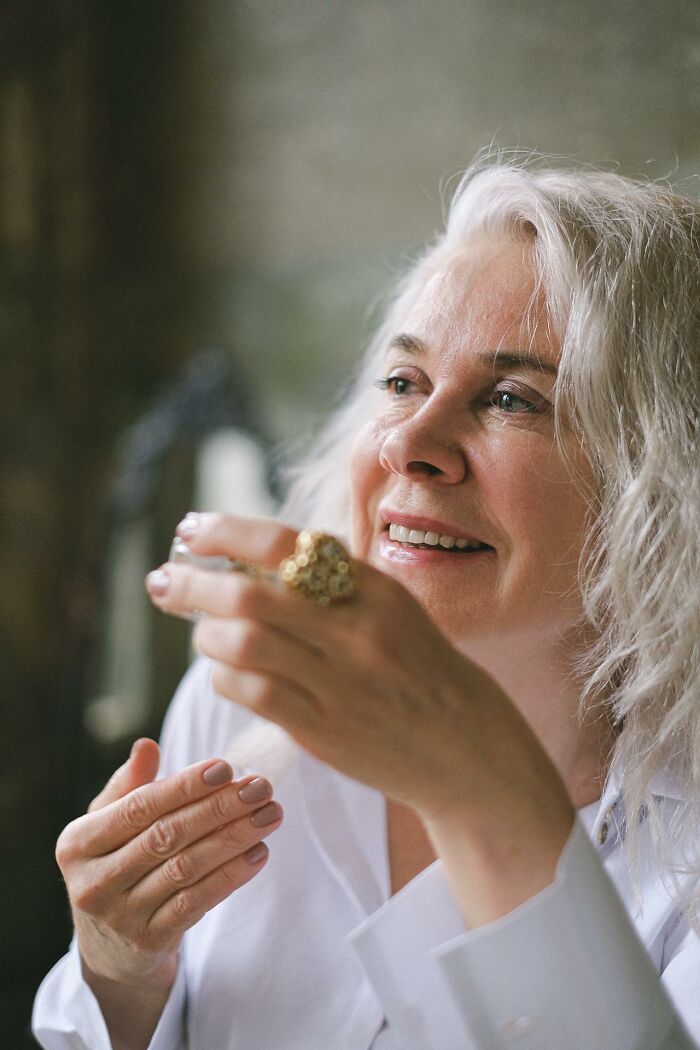Smiling mature woman with gray hair taking a thoughtful pause while holding a cup, illustrating moments of pause after stupid things said.