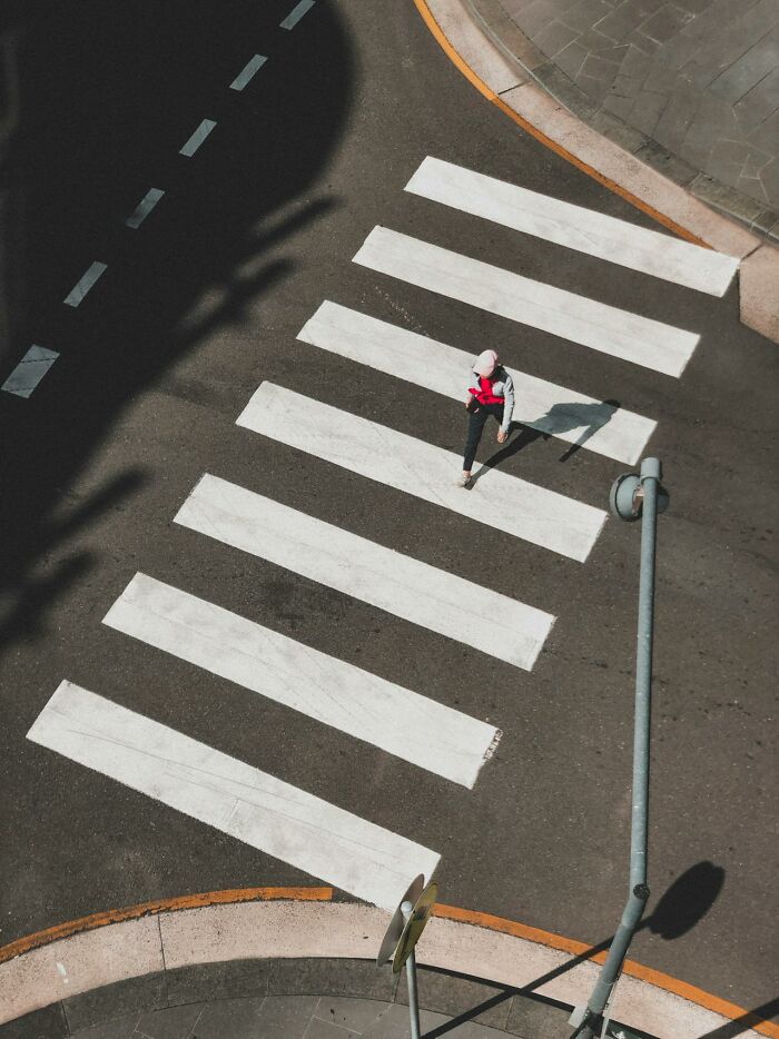 A person walking alone on a crosswalk, representing silent judgment by people in everyday situations.