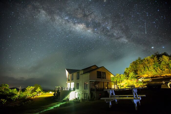 Night sky filled with stars and the Milky Way above a rural house, evoking strange things people witnessed beyond Earth.