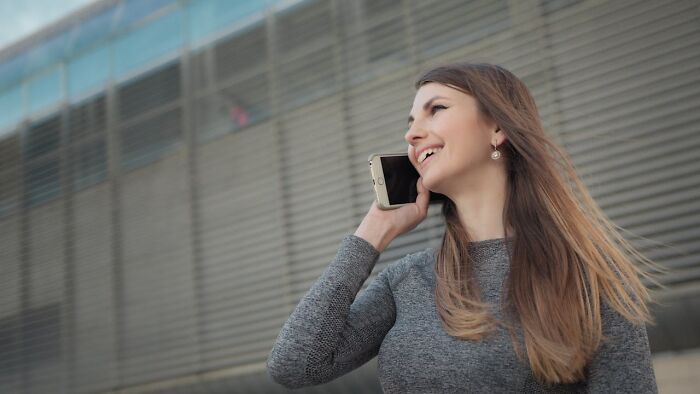 Young woman with long hair smiling and talking on phone, illustrating women traumatized men keyword concept.