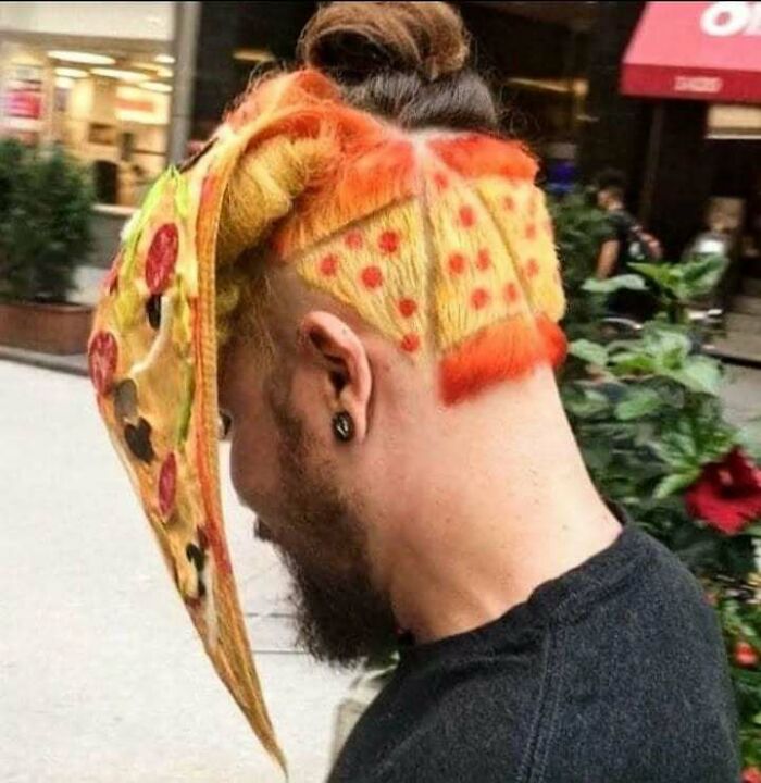 Man with hilarious pizza-themed haircut and a large pizza slice prop, showcasing unique and funny meme-worthy style.