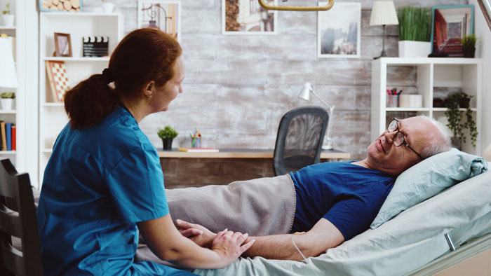 Elderly man lying in bed holding hands with a caregiver, showing emotional support and care in a cozy room. Elderly man lying in bed holding hands with a caregiver, showing emotional support and care in a cozy room.
