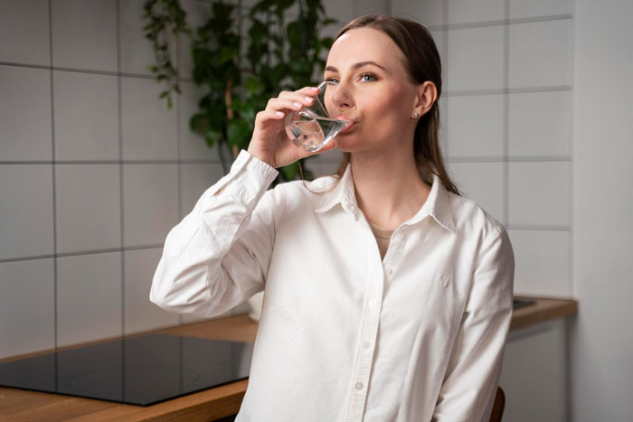 Woman in a white shirt drinking water from a glass, representing pill relationship challenges and boyfriend bullying awareness. Woman in a white shirt drinking water from a glass, representing pill relationship challenges and boyfriend bullying awareness.