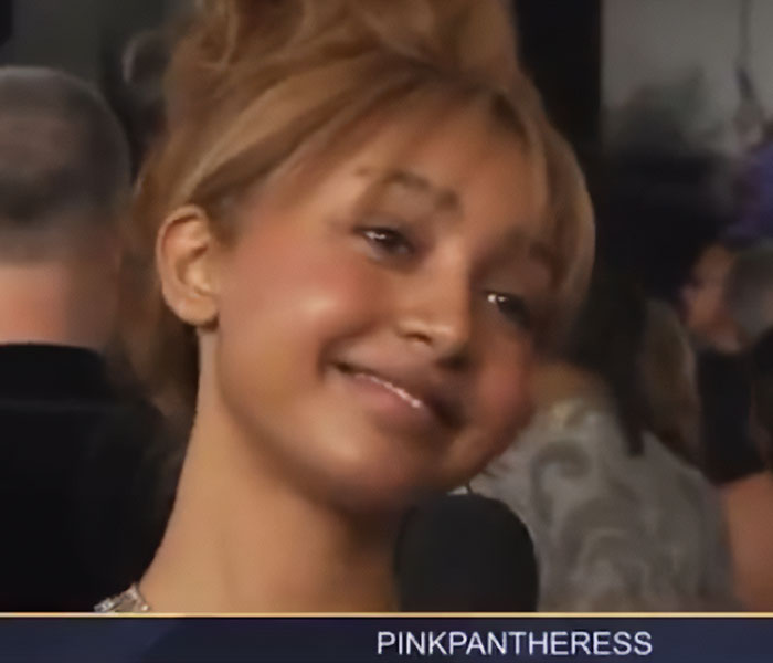 Young woman smiling awkwardly during celebrity reactions at the 2026 Grammy Awards event interview.