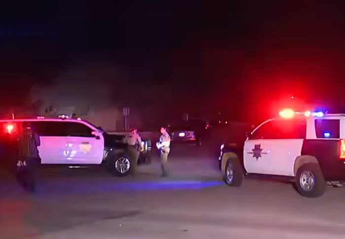 Police vehicles with flashing lights and officers at night investigating a scene related to a kidnapping case.