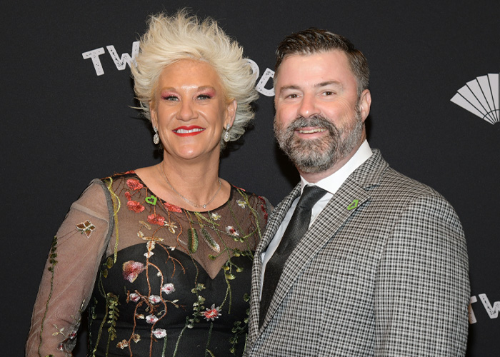 Anne Burrell with a man at an event, posing in front of a black backdrop, related to police report on tragic passing details. Anne Burrell with a man at an event, posing in front of a black backdrop, related to police report on tragic passing details.