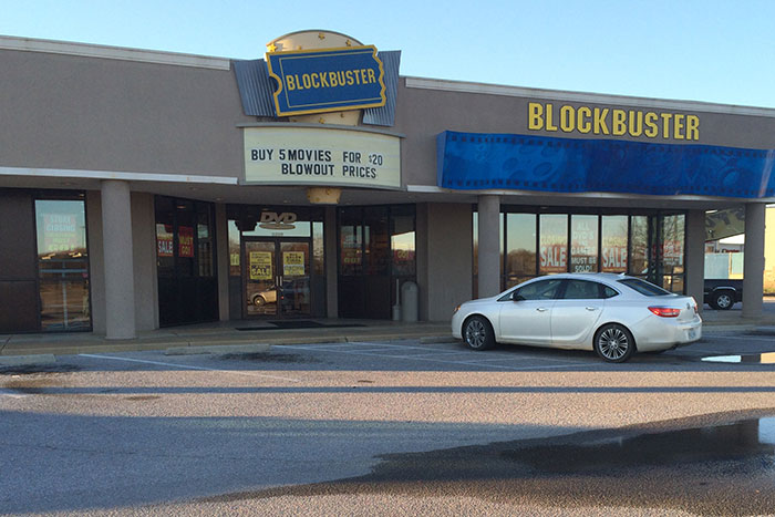 Exterior of a closed Blockbuster store with sale signs, illustrating a fast decline and coworker stories about quick firings.