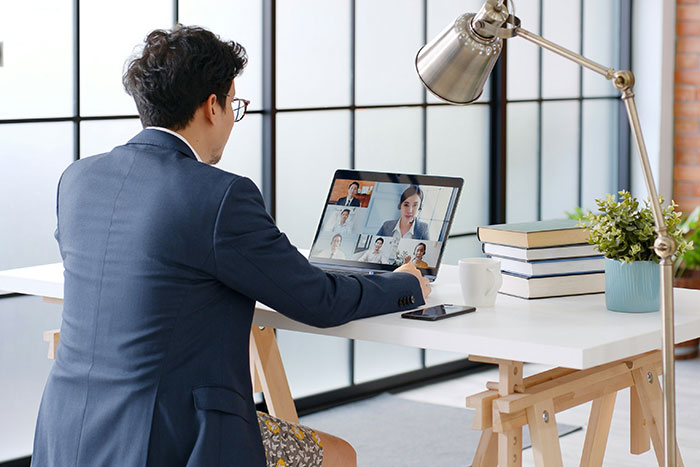 A man in a suit attending a virtual meeting on laptop, symbolizing fast coworker firing experiences.