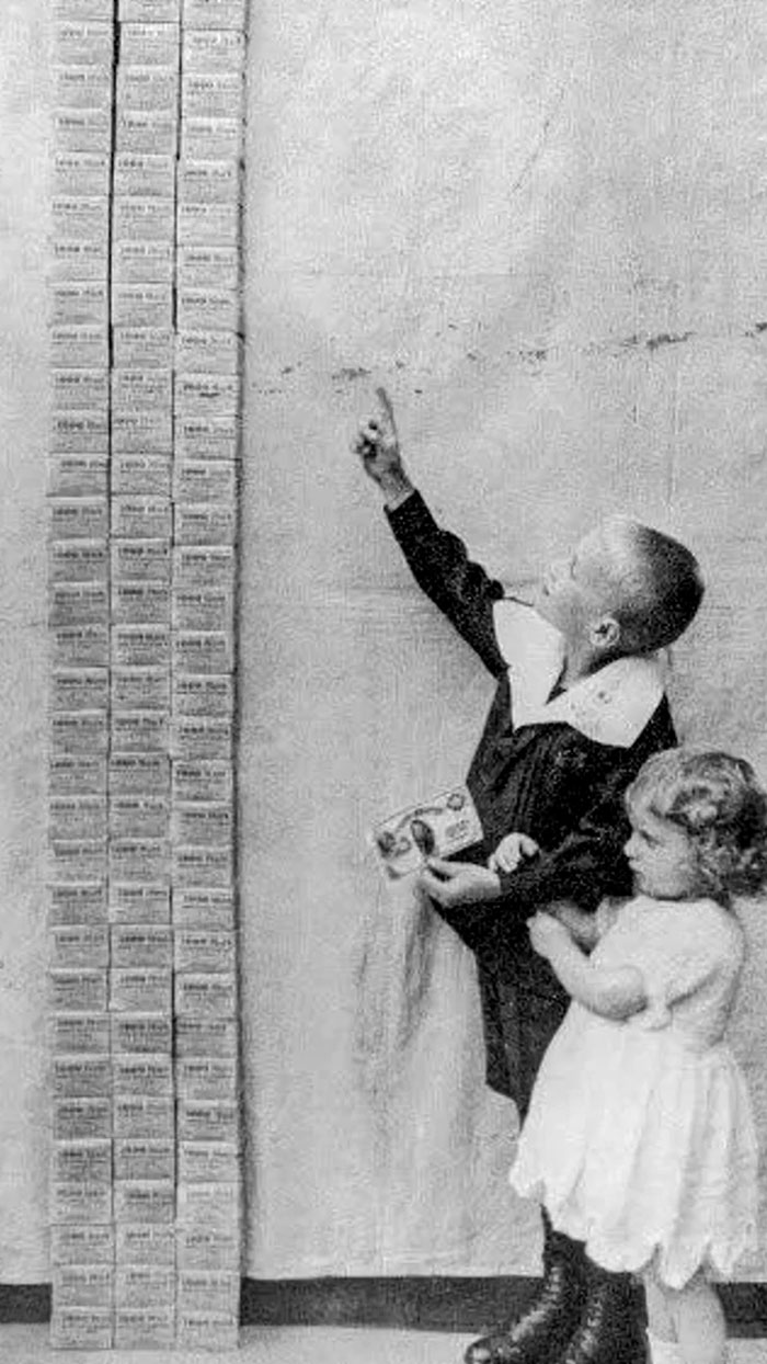 Two children examining a tall stack of vintage ration cards in a rare and intriguing history photo.