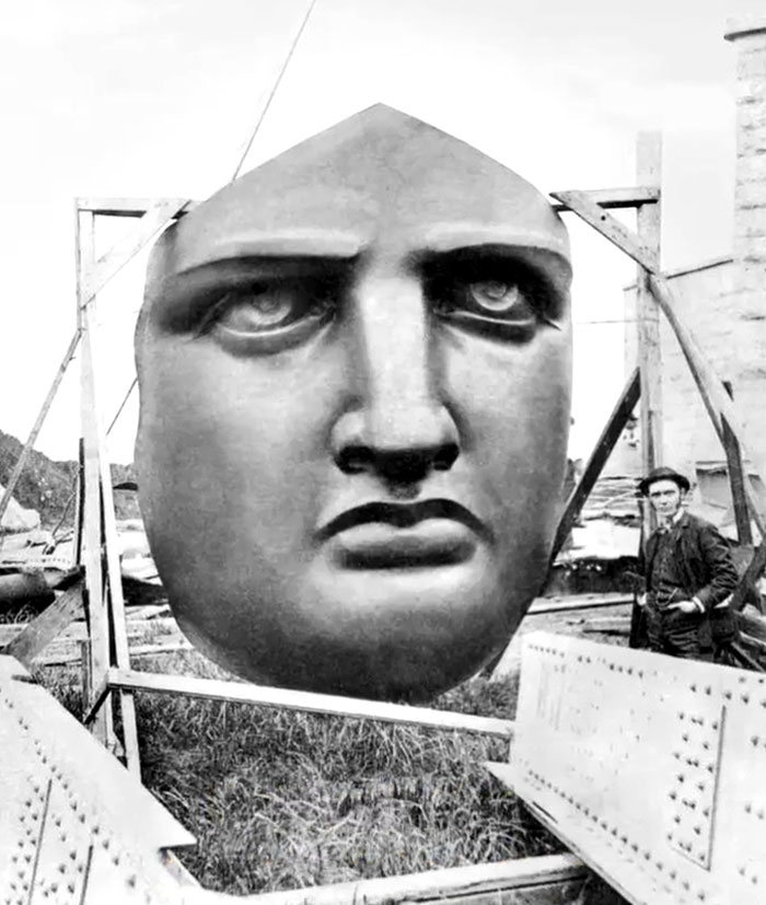 Large historic face sculpture displayed outdoors with a man standing nearby, showcasing rare and intriguing photos of history.